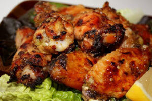 Grilled Spicy Thai Chicken Wings glazed with sweet and spicy Thai sauce, garnished with green onions and sesame seeds.