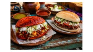 Mexico City-style red pambazo with potato and chorizo beside a Veracruz-style pambazo with beans, chorizo, lettuce, cheese and tomato.