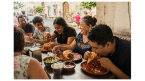 Local diners enjoy sauce-drenched tortas ahogadas with chile salsa, onions, and lime at a neighborhood eatery in Guadalajara.