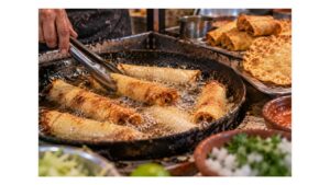 Mexican street-food cook frying rolled tacos until crisp and golden beside a finished tostada, showing how frying transforms corn tortillas into crispy street foods.